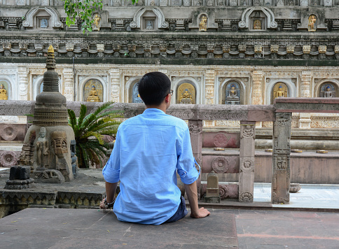 An Asian man practicing yoga meditation at a monastery.