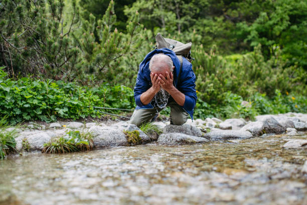 istock Active senior man washing his face in mountain stream. 1609305364