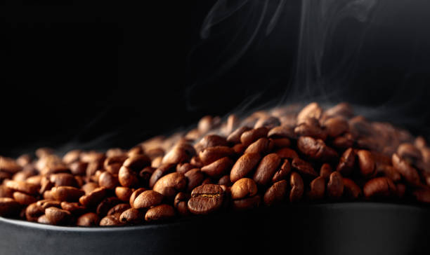 Steaming coffee beans on a black background. stock photo