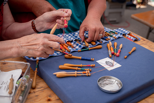 Hands of people preparing and making bobbin lace. Colorful lace threads. Leisure activity.