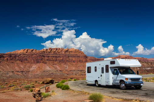 white RV / campervan in canyonlands USA with red cliffs and blue sky behind it