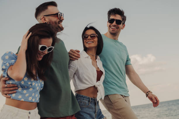 istock Group of joyful young people bonding and smiling while walking by the beach together 1609409401
