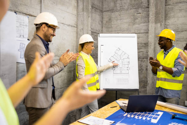 istock Motivated and positive group of structural engineers at construction site meeting laughing and clapping hands. 1609420083