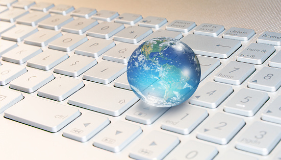 Glass globe on blured laptop keyboard 