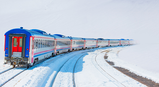 Red diesel train (East express) in motion at the snow covered railway platform - The train connecting Ankara to Kars - Passenger train going through tunnel
