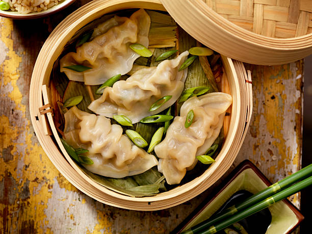 Steamed Dumplings Steamed Dumplings in a bamboo steamer with bamboo leaves, fresh green onions, soya sauce and rice -Photographed on Hasselblad H1-22mb Camera chinese dumpling stock pictures, royalty-free photos & images