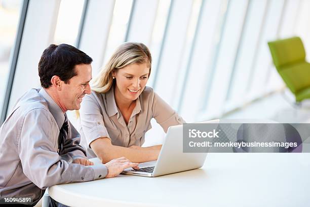 A Man And A Woman Work In Front Of A Laptop In An Office Stock Photo - Download Image Now