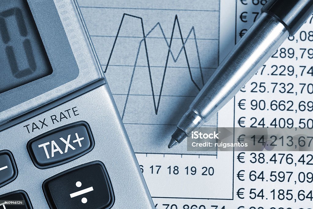 TAX Detail of calculator, focusing the TAX key, next to a sheet of paper with numbers and a metal pen Business Stock Photo