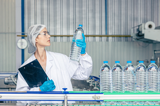 worker in drinking water factory. women workers caucasian labor in beverage clean production conveyor belt mineral water manufactory.