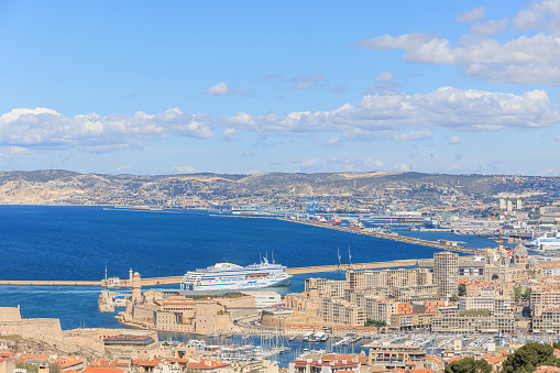 A scenics aerial view of the city of Marseille, bouches-du-rhône, France with a cruise ship arriving at the port under a majestic blue sky and some white clouds