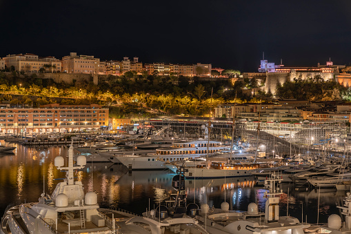 NIght landscape of Monaco. Aerial view. View of Skyline, Hercules Port in Monaco, Monte Carlo. Many luxury yachts and grandstand of Monaco open-wheel single-seater racing car Grand Prix and mountains in the background.