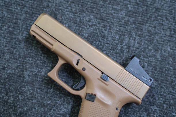 istock Camouflage colored pistol on the table, close up photo 1609499294