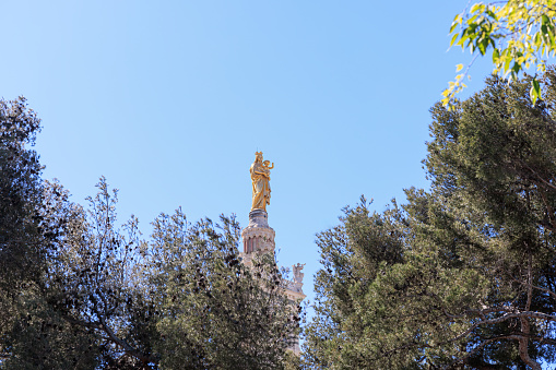 A scenics view of the Basilique Notre-Dame-de-la-Garde, la Bonne Mère gold statue,  Marseille, bouches-du-rhône, France under a majestic blue sky