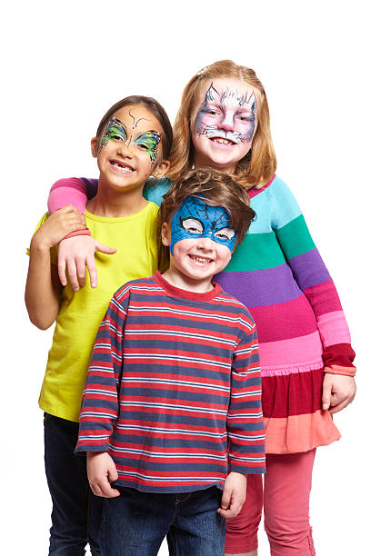 Young boy and two girls with face painting Young boy and two girls with face painting of cat, butterfly and superhero smiling on white background face paint stock pictures, royalty-free photos & images