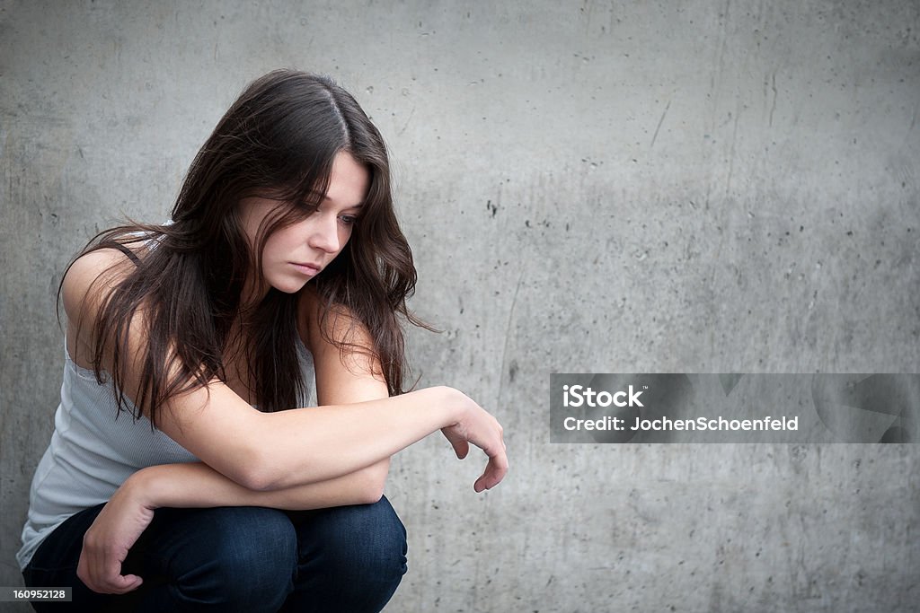 Teenage girl looking thoughtful about troubles Outdoor portrait of a sad teenage girl looking thoughtful about troubles in front of a gray wall Teenage Girls Stock Photo