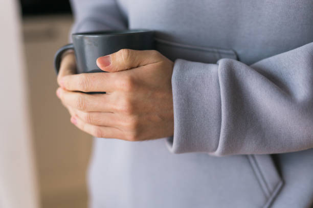 istock Close-up man with cup of coffee. Guy drinks coffee sitting near window 1609525769
