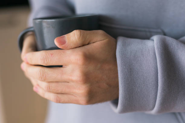 istock Close-up man with cup of coffee. Guy drinks coffee sitting near window 1609528454