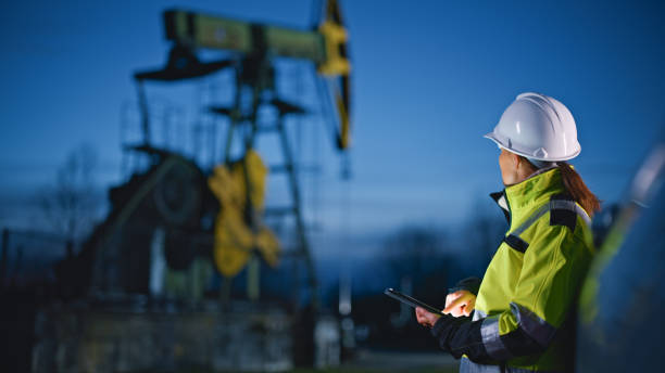 ingénieur regardant des machines tout en utilisant une tablette pc à l’industrie pétrolière contre ciel - engineer oil rig oil field manual worker photos et images de collection