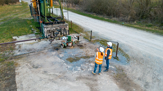 High angle view of male and female workers discussing over equipment while standing on oil field during winter