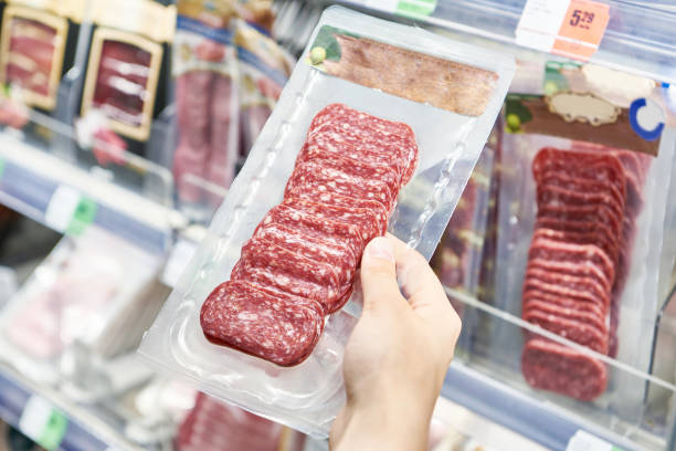 istock Sliced sausage in plastic pack in hands in store 1609596576