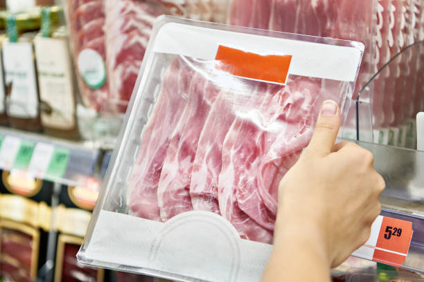 istock Sliced prosciutto meat in package in hand 1609596584