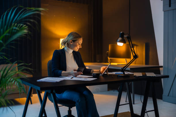 Female entrepreneur working on digital tablet till late at workplace