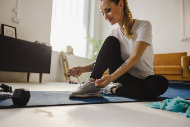 istock Woman tying shoelace while sitting on exercise mat 1609603846