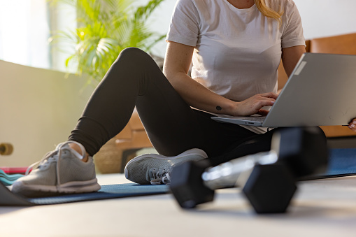 Low section of young woman using laptop after workout in living room at home