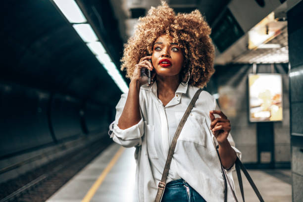 istock Beautiful Afro woman standing at subway station platform 1609604328