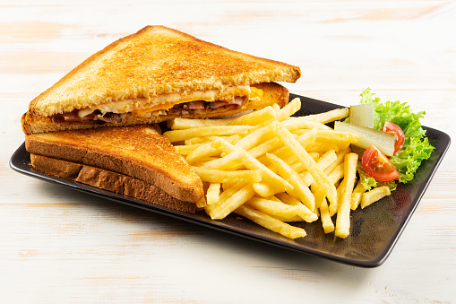 Îreakfast sandwich with bacon, cheese and pan fried potatoes.