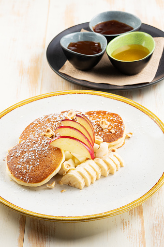Îreakfast concept. Pancakes with fruits and syrup on wooden background.