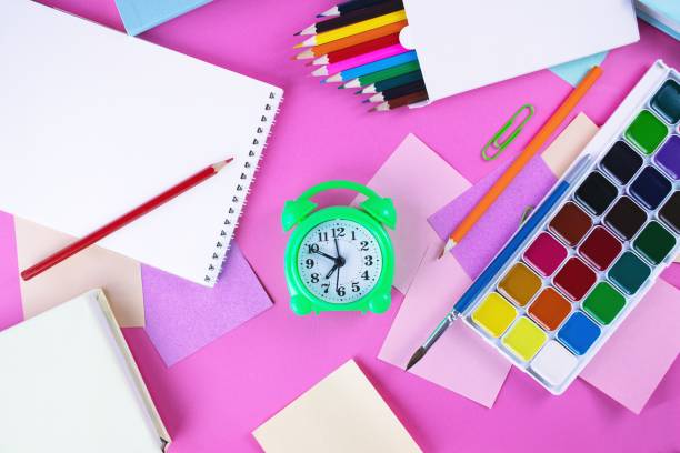 istock Back to school concept with colored pencils, stickers, alarm clock and notepad on pink background 1609654128