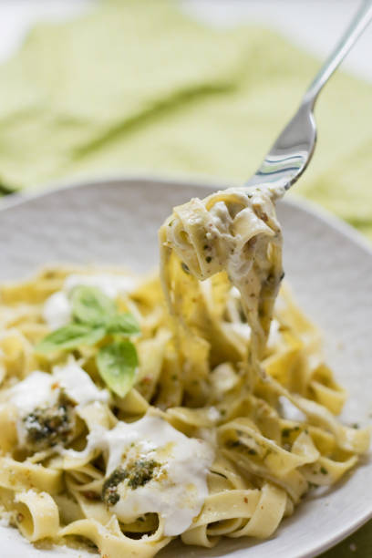 Homemade tagliatelle pasta with pesto sauce and stracciatella di bufala cheese on a plate