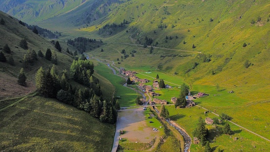 This aerial shot captures a stunning view of a valley surrounded by lush green hills and mountains