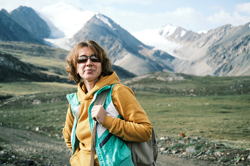 Cheerful female tourist is looking at view on mountain road
