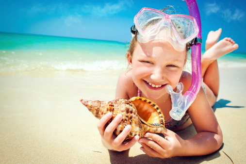 Little girl after snorkeling with the shell on the beach