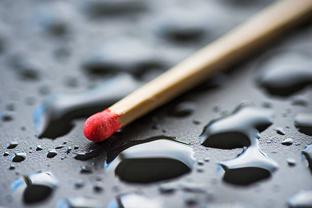 Dry match and raindrops on black metal surface Closeup unused matchstick lying on black wet surface covered with droplets of water unlit match stock pictures, royalty-free photos & images