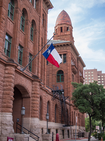 Discover the rich history and stunning architecture of the Bexar County Courthouse, a true Texas landmark that proudly stands in the heart of downtown San Antonio. Built in the late 1800s, this grand courthouse boasts a majestic neoclassical design, complete with towering columns and a grand dome that soars into the sky. The star of Texas proudly waves in the breeze, adding to the already impressive scene. This iconic courthouse has served as a symbol of justice and democracy for generations of Texans, and its grand facade and rich history make it an ideal subject for any photography collection. This stunning photograph captures the very essence of Texas pride and heritage, and is a must-have for any lover of American history and architecture.