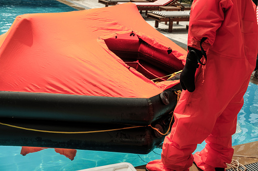 stcw life raft training maritime course in the swimming pool, people wearing waterproof suits