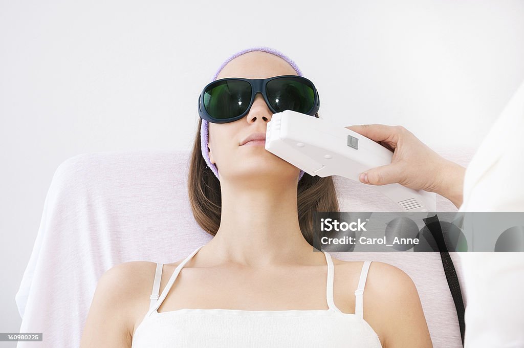 A young woman with a laser treatment machine on her face Young woman receiving laser epilation treatment Medical Laser Stock Photo