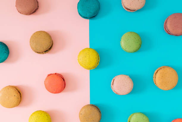 istock Creative colorful pattern made of various macarons on pastel pink and blue background. Minimal sweet food concept. Trendy macaron cookies pattern background. Yummy flat lay idea. 1609812963