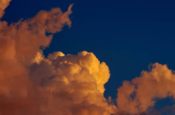 istock Fluffy clouds tinted orange by the sunset 1609813194