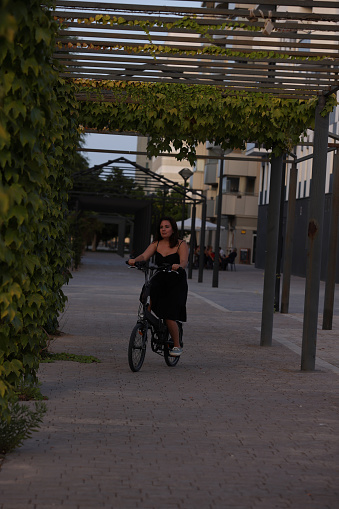 Young lady riding electric bicycle in the evening