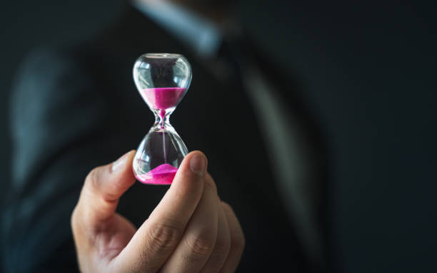 Business person holding hourglass in hand stock photo