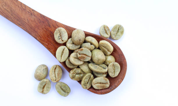 istock Green coffee beans in a wooden spoon top view 1609814332