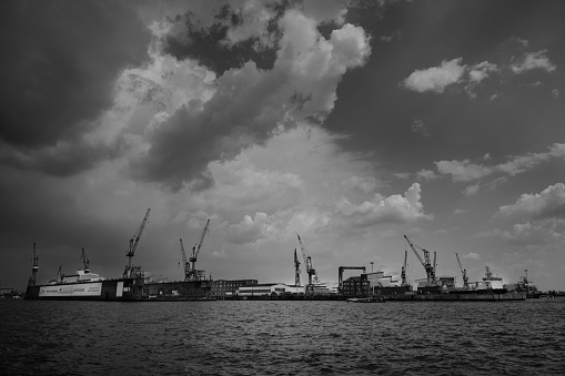 Hamburg, Germany - June 17 2023: Blohm und Voss Swimming Dock 11 on the Elbe River with Cranes in a Dramatic Black and White Urban Landscape