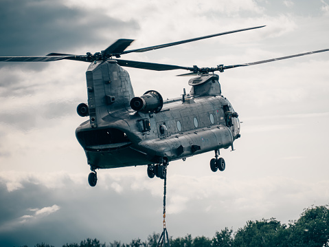 An RAF CH-47 Chinook hovering in training carrying a vehicle beneath (out of view)