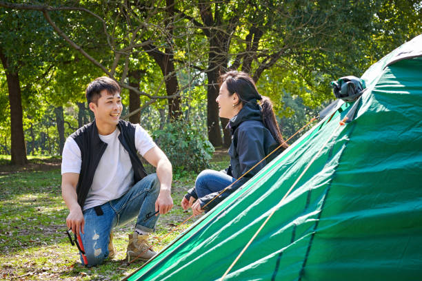 istock Man & Woman Putting-up Tent at Camping Trip 1609818384