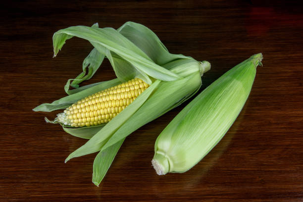 istock Sweetcorn Cobs on a Polished Wooden Table Top Closeup View 1609824442