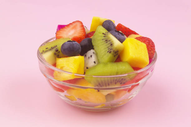 istock Fruit salad in glass bowl on pink background 1609829958